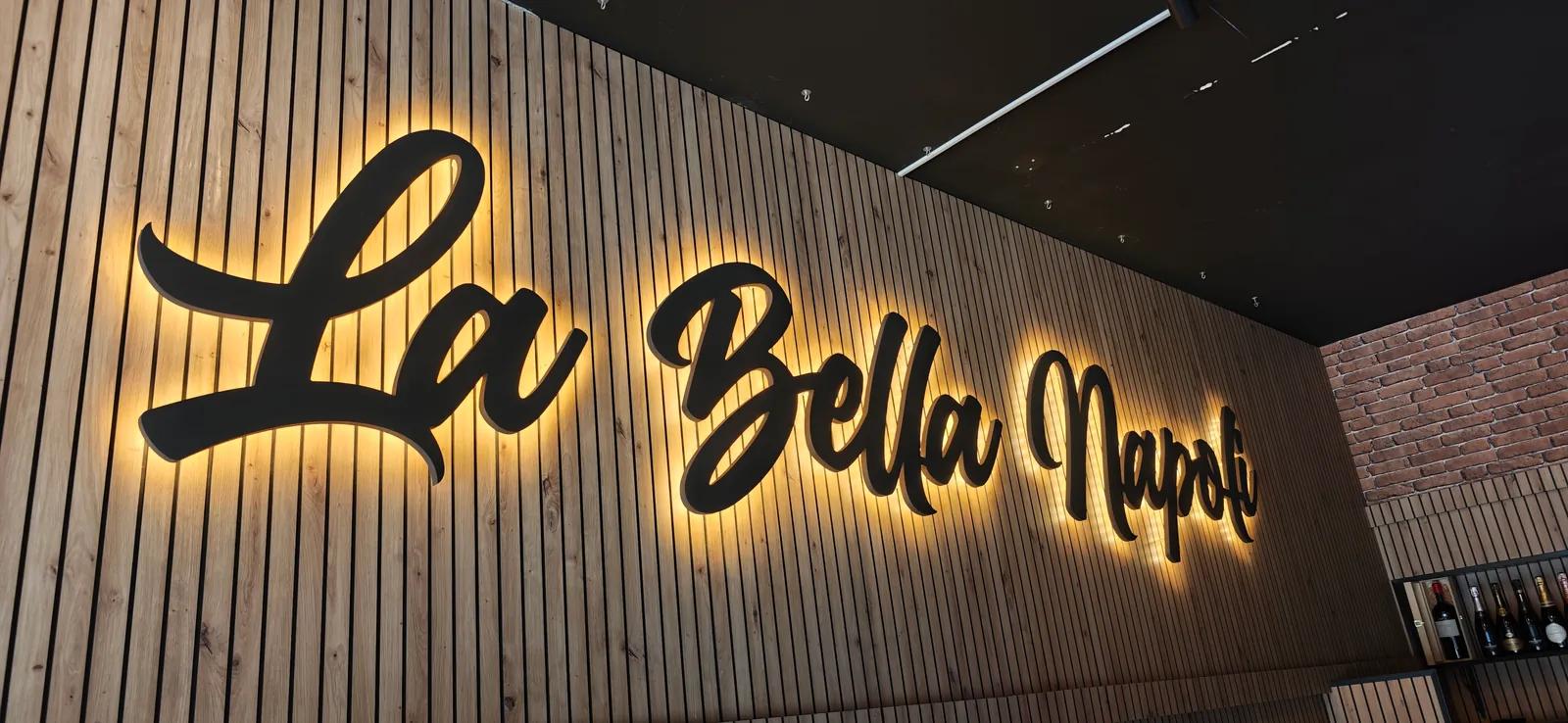 Trabajo real de letras corpóreas retroiluminadas sobre madera en un restaurante