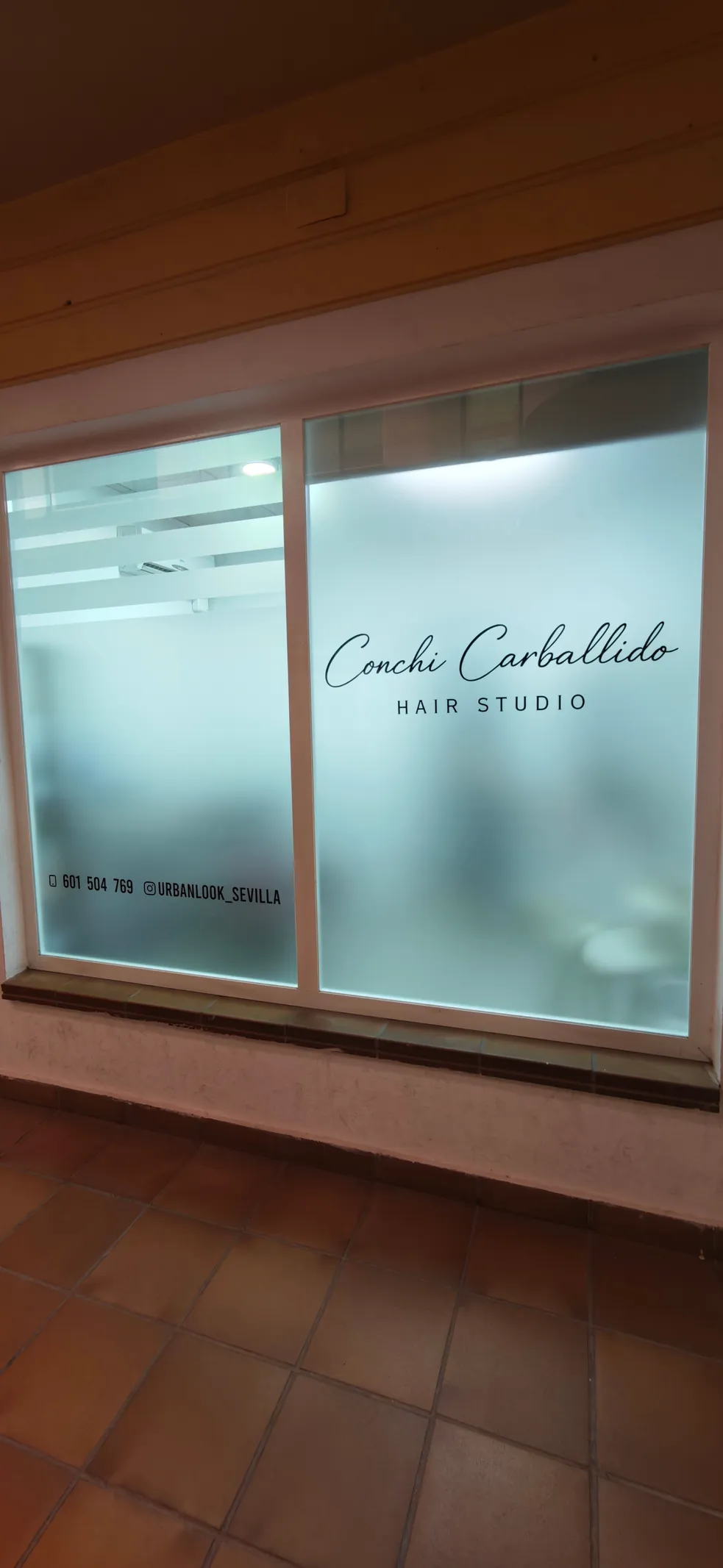 Trabajo real de vinilo ácido con rotulación en el cristal de una peluquería